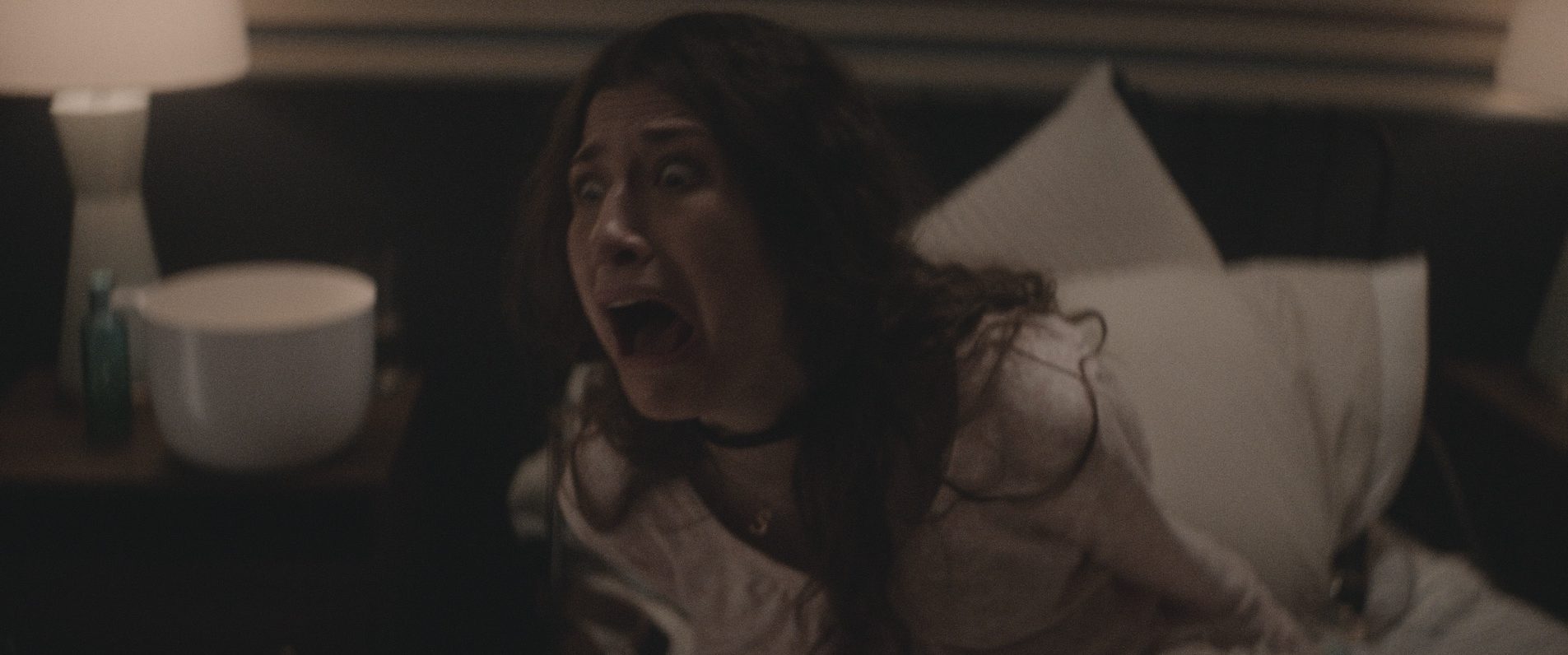Captive pregnant woman [Konstantina Mantelos] screaming in horror at demons appearing in her room. Photo credit: Dyck, Justin. dir. Anything For Jackson. 2020.